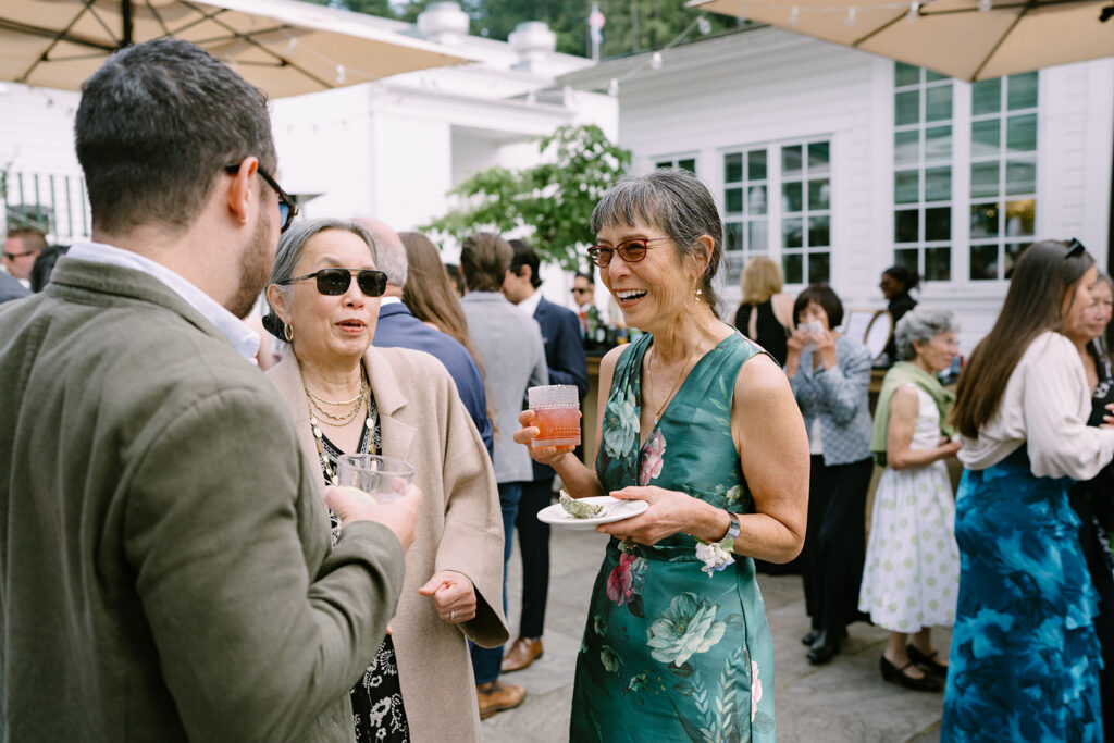 Cocktail hour at Roche Harbor Resort — guests gathering on the outdoor patio with the marina and PNW treeline as the backdrop.