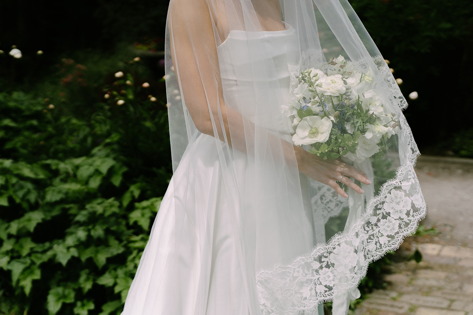 Detail shot of the lace-trimmed cathedral veil and white garden bouquet at this San Juan Island summer wedding.