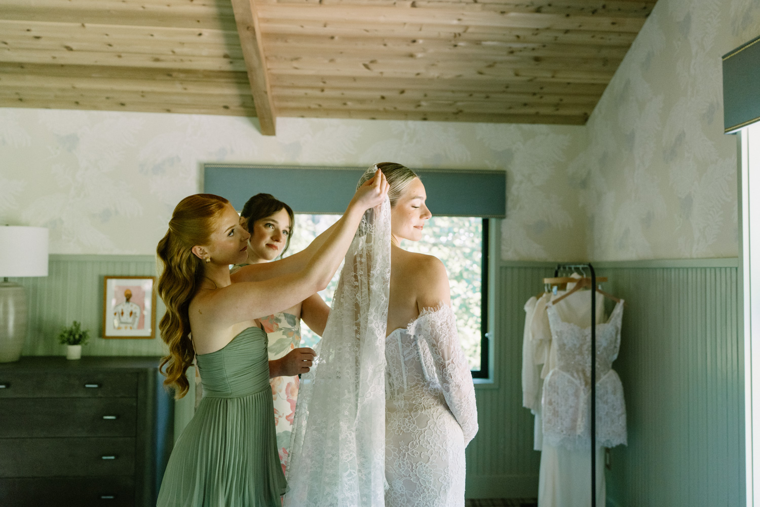 Bridesmaids help a bride put her veil on in a getting ready space at the Carly Estate wedding venue.
