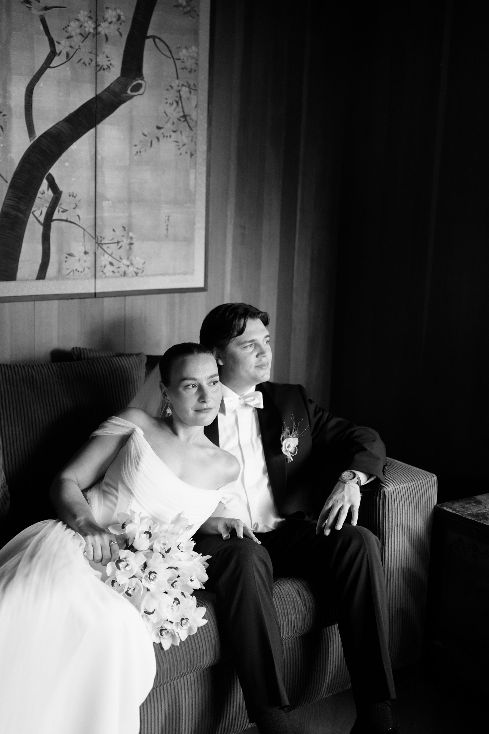 Couple sitting close together on a sofa in the Kingston House interior, one holding a bouquet