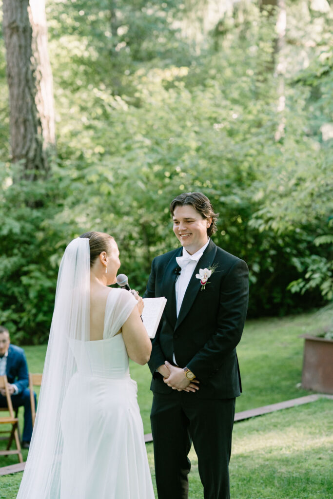 Couple exchanging vows on the lawn clearing at their Anker Place wedding, ringed by tall trees