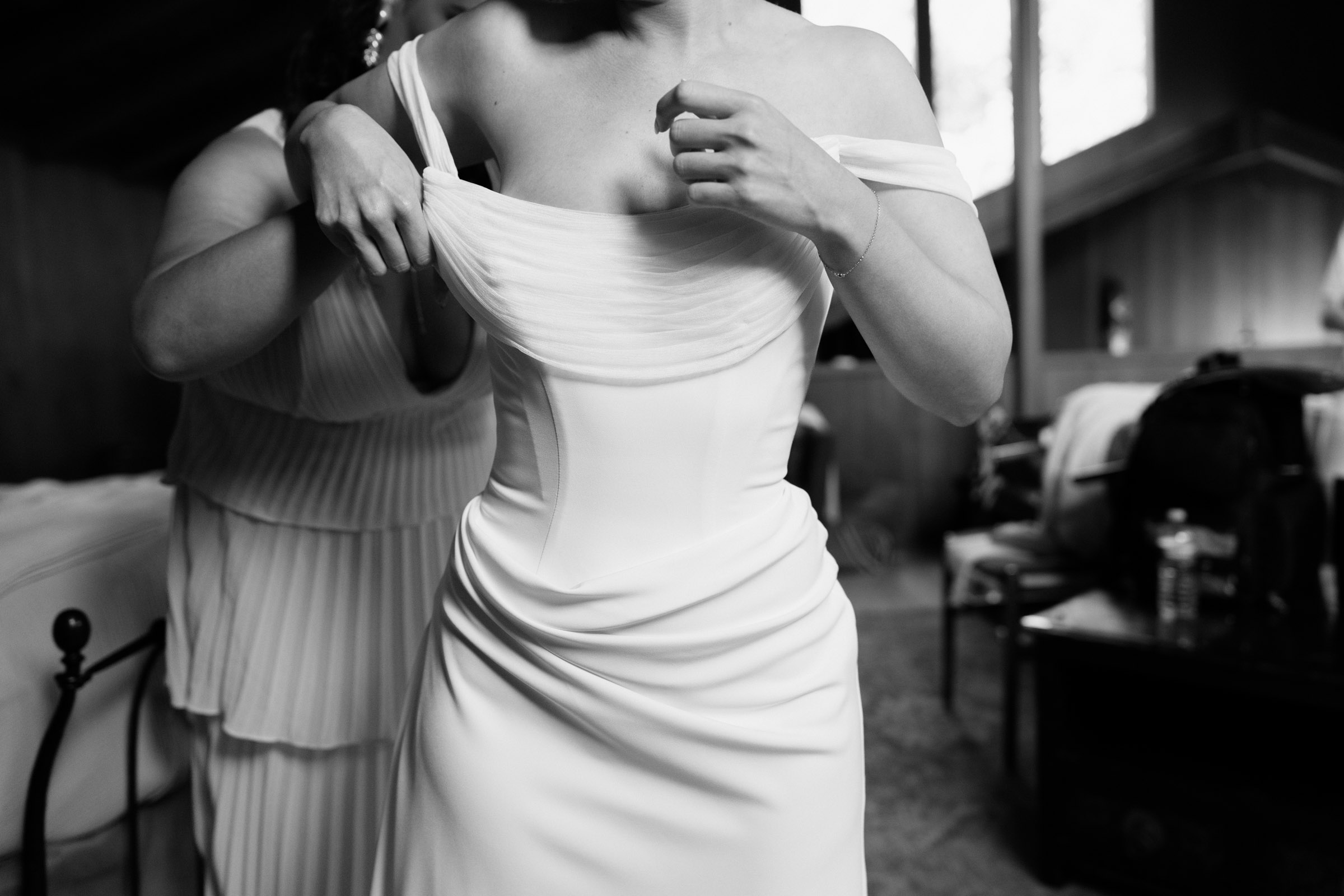 Stepping into the wedding gown at Anker Place as an attendant adjusts the off-shoulder neckline