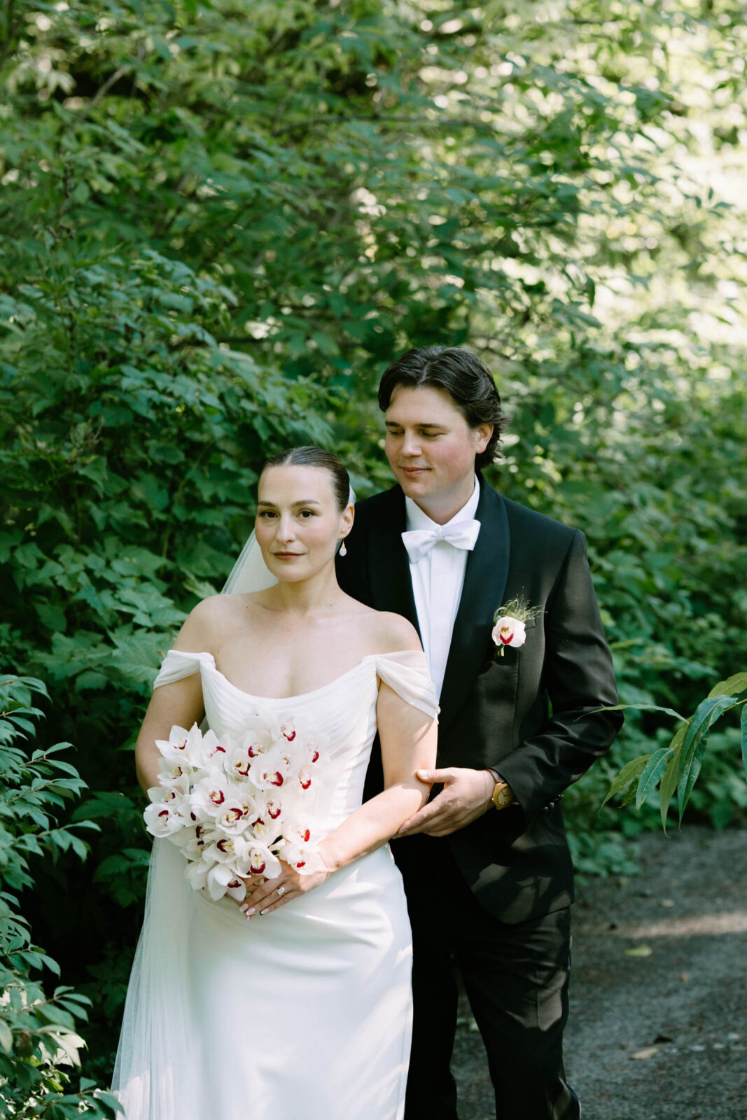 Couple at their first look in the Anker Place gardens, one in a gown holding a floral bouquet