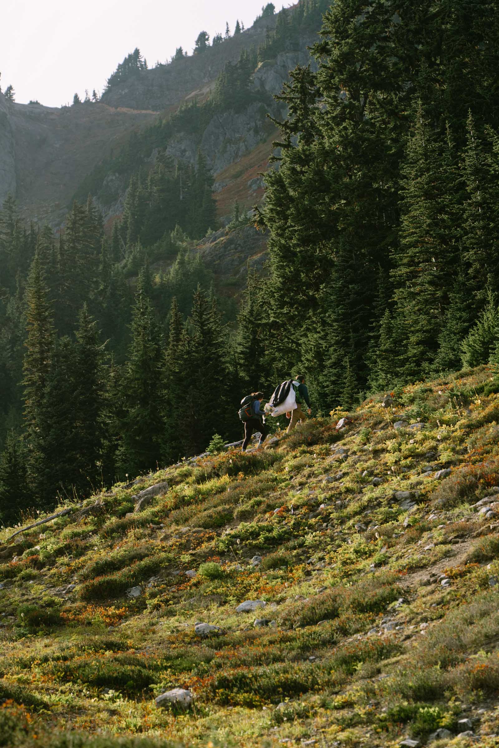 Couple hiking with backpacks on the trail to their Winchester Mountain lookout elopement