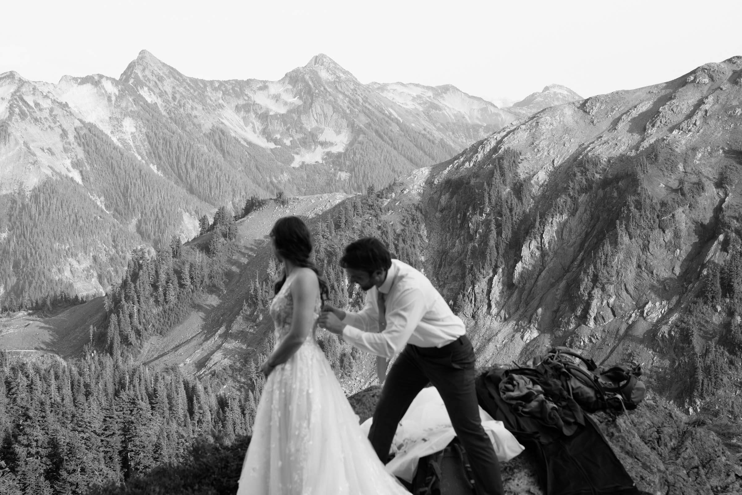 Couple in elopement attire on a ridge with North Cascades peaks behind them